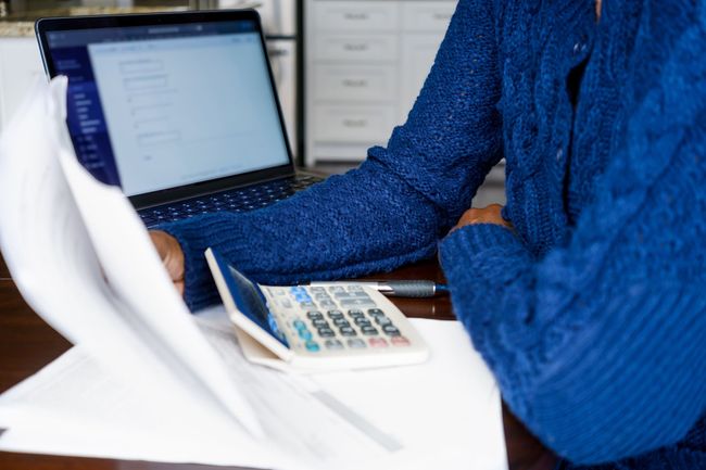 A woman is sitting at a table with a laptop and a calculator.