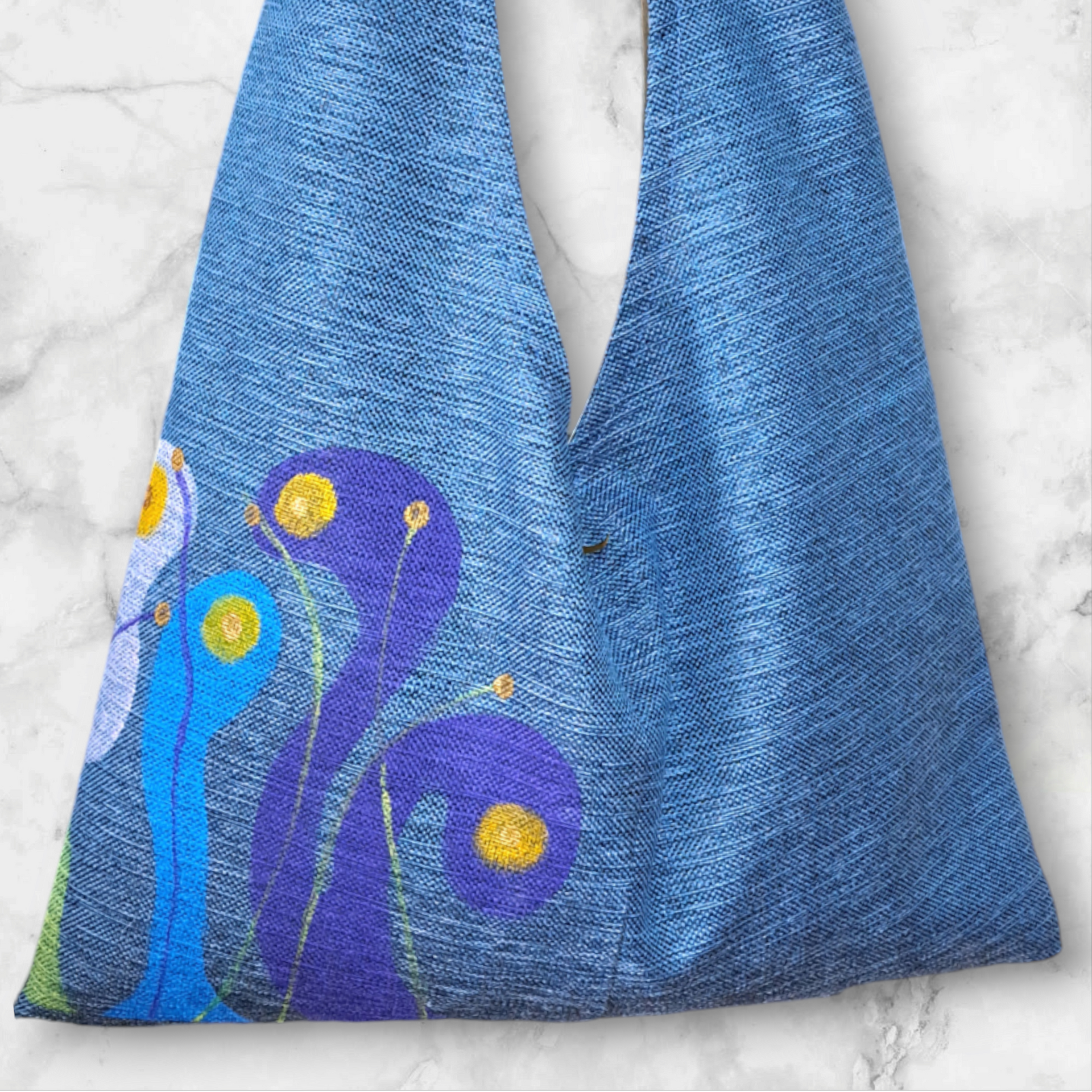 Una bolsa azul con flores moradas y amarillas.