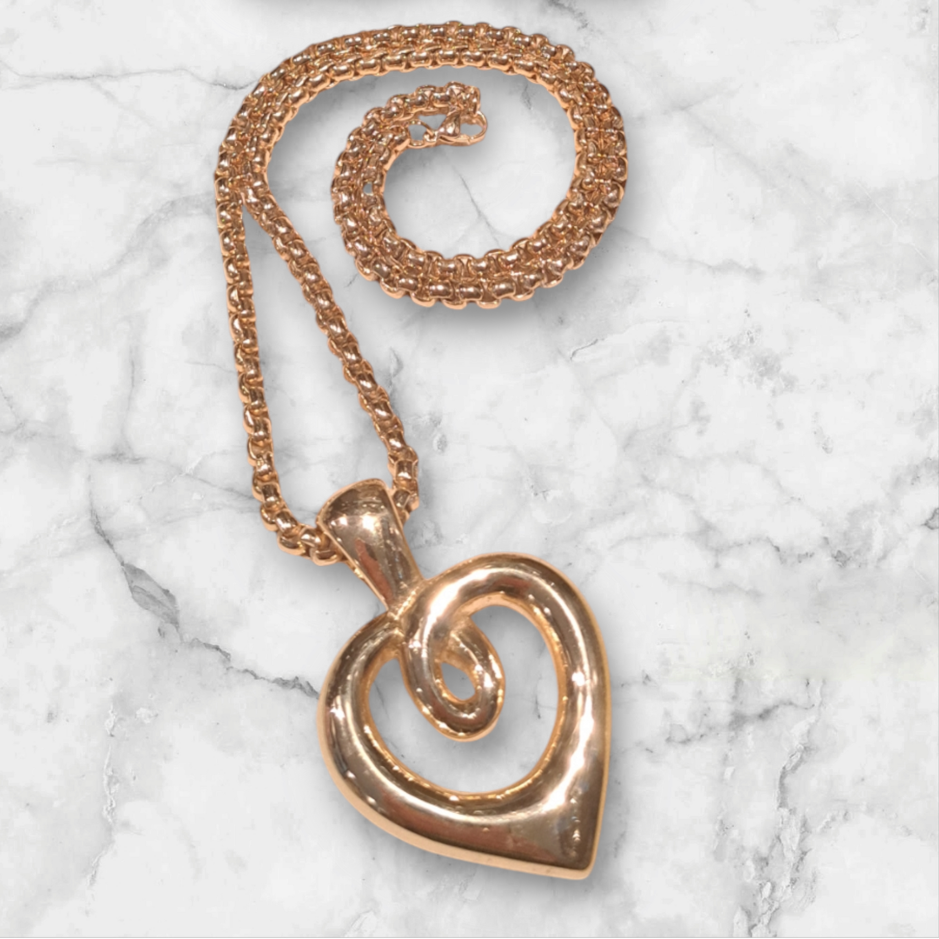 Un collar de oro con un colgante en forma de corazón en una cadena.