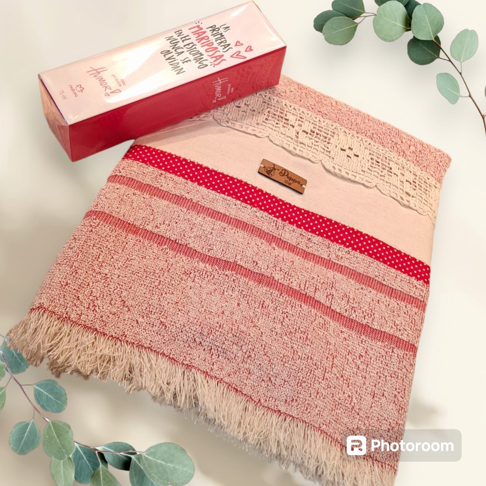 Una toalla rosa está junto a una caja de perfume.