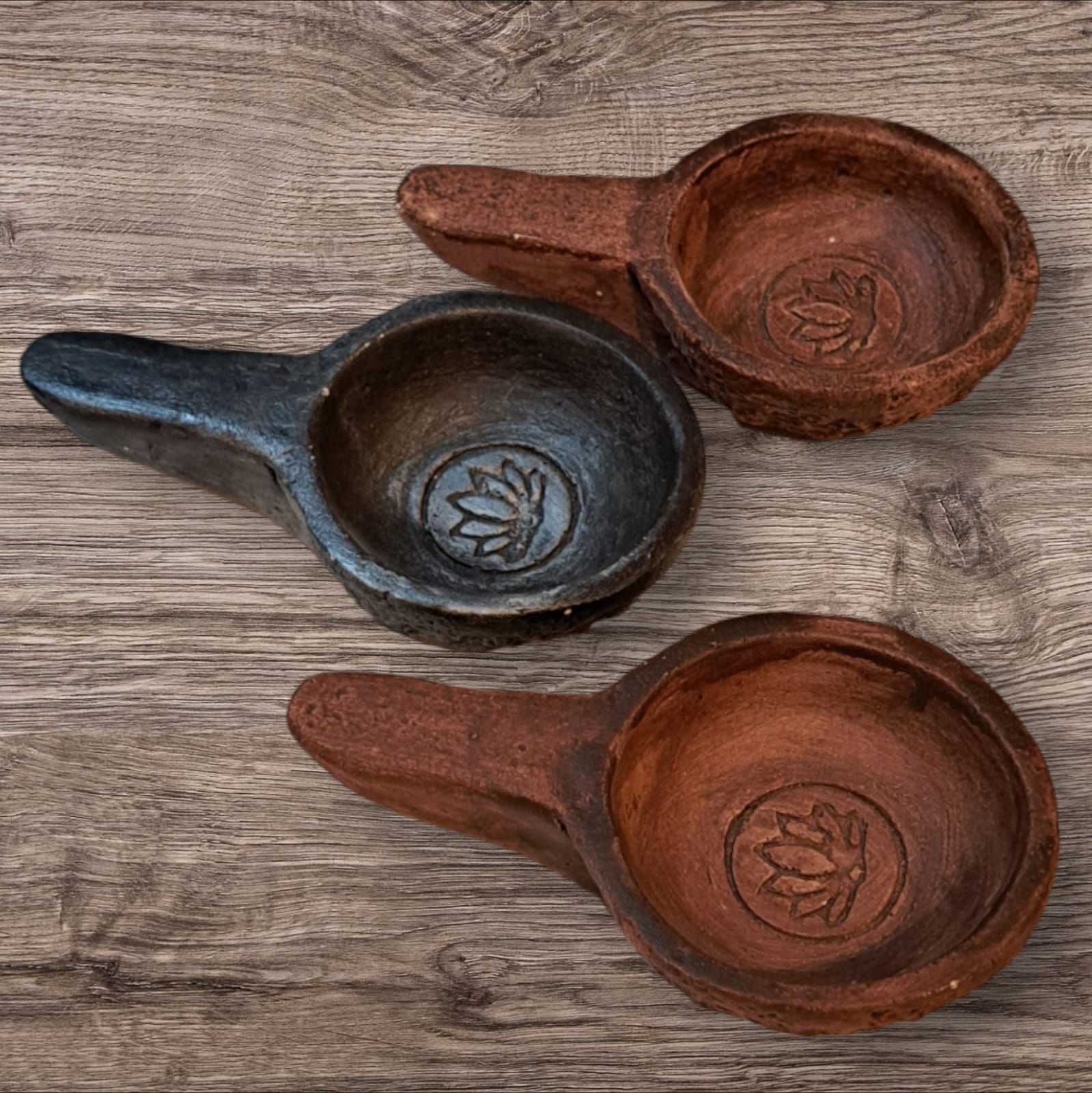 Tres cuencos de madera con asas están sobre una mesa de madera.