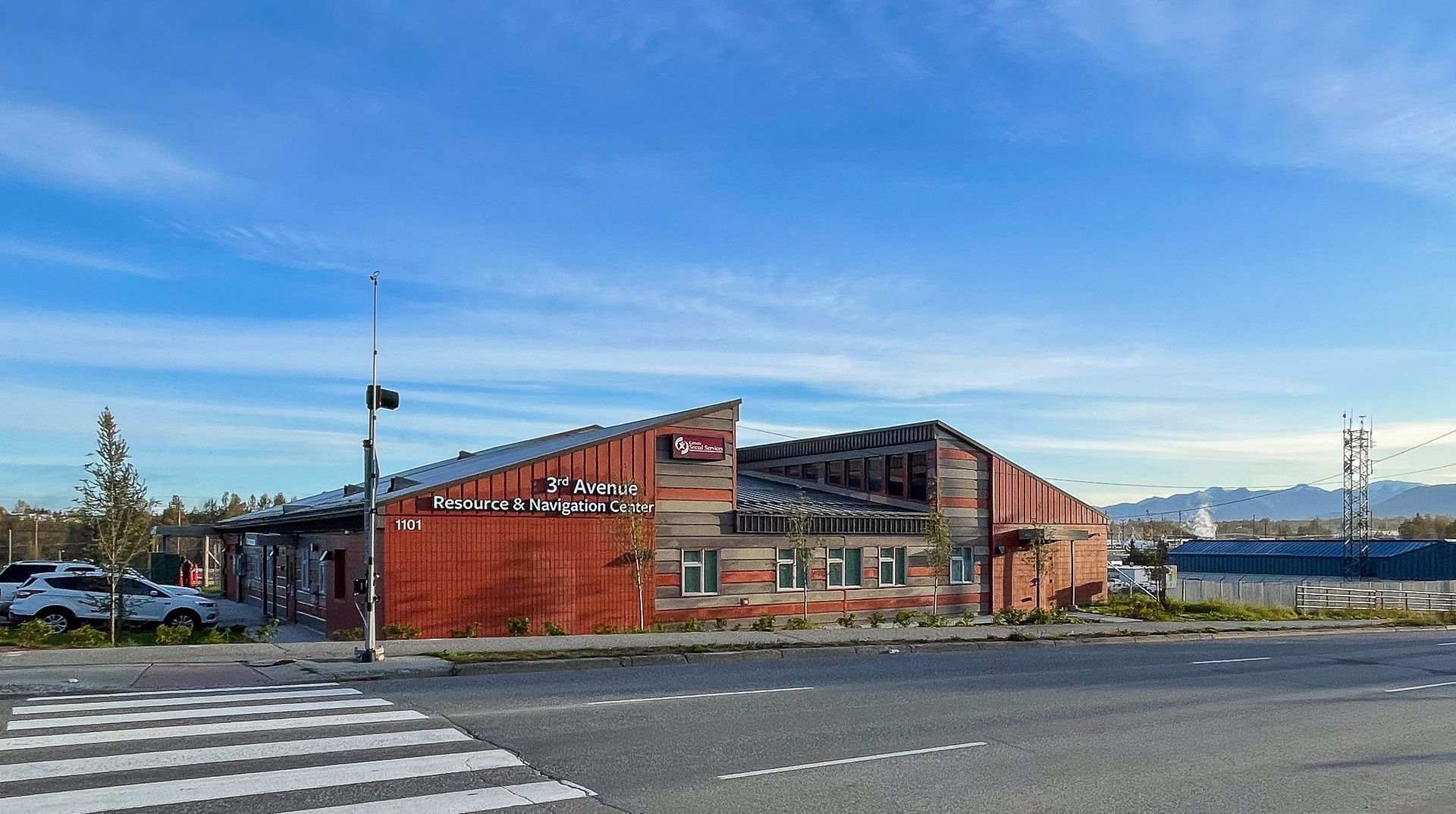 A red wooden restaurant building with a sloped roof sits by a road with a crosswalk under a clear, bright blue sky.