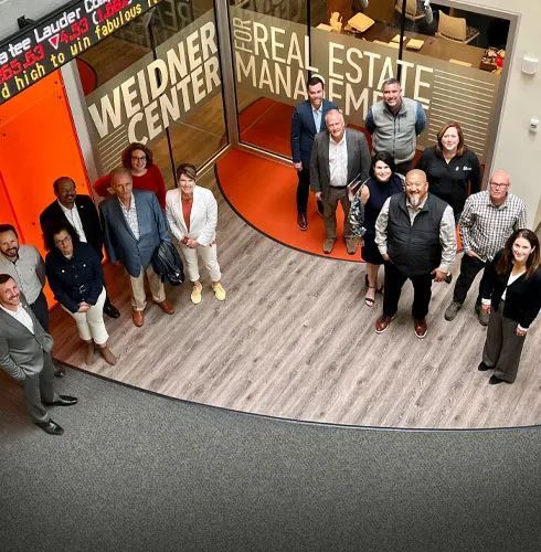 The Leavenworth Village Inn with a wooden sign, stone pillars, and green landscaping under a bright blue sky.