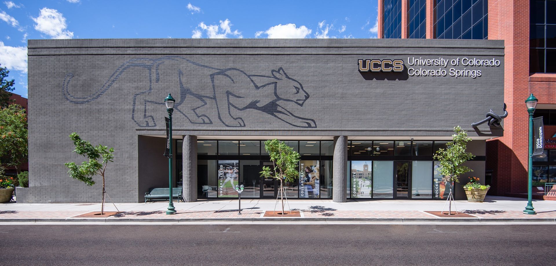 Exterior view of the UCCS building in Colorado Springs with a mountain lion mural on the grey concrete facade.