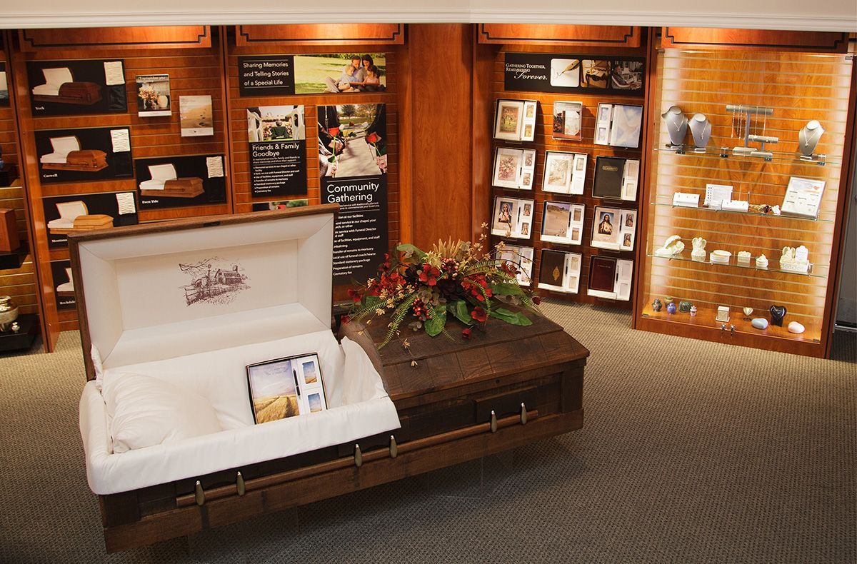 International Funeral Service Show Room: Wood-paneled memorial display with white casket, flowers, and framed photos
