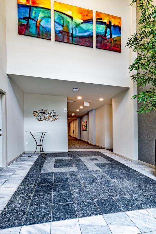 Entryway with colorful abstract art, tiled floor, and a long hallway.