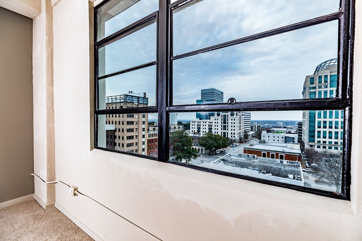 View from a window looking over a city with buildings and a cloudy sky.