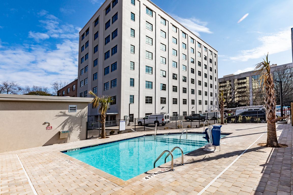 A swimming pool in front of a tall apartment building on a sunny day.