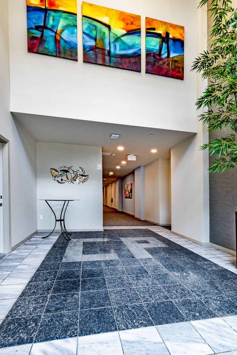 Hallway with modern art, black tile floor, and abstract painting above entryway.