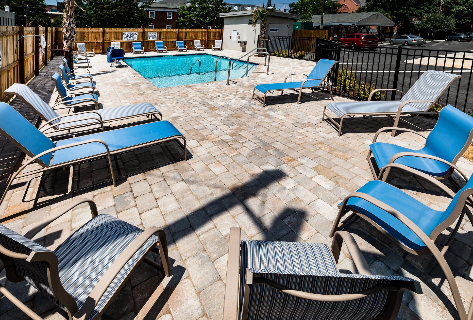 Poolside seating area with blue and white lounge chairs. Stone patio surrounds a small pool.