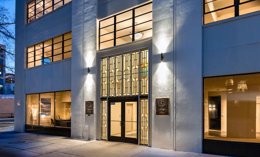 Modern building entrance with glass doors, windows, and warm lighting.