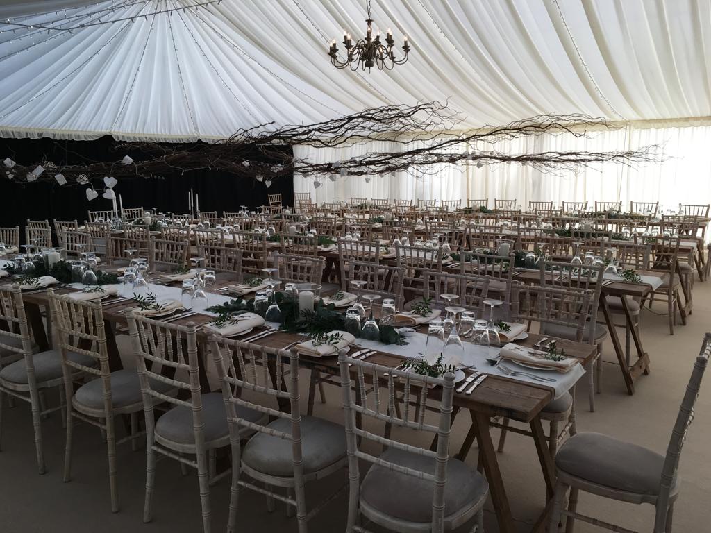 A large tent with tables and chairs set up for a wedding reception.