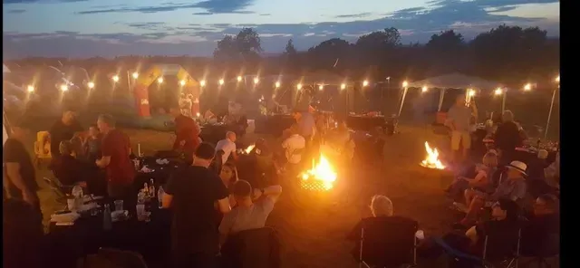 A group of people are sitting around a campfire at night.