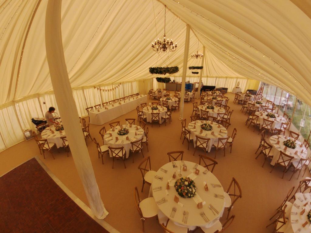 A large tent with tables and chairs set up for a wedding reception.