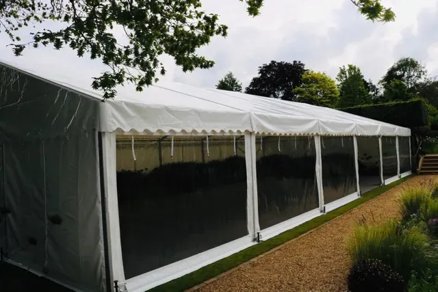 A large white tent is sitting on top of a gravel path.