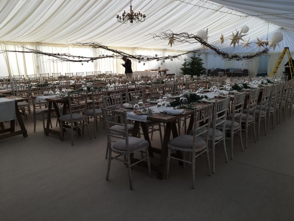 A large tent with tables and chairs set up for a wedding reception.