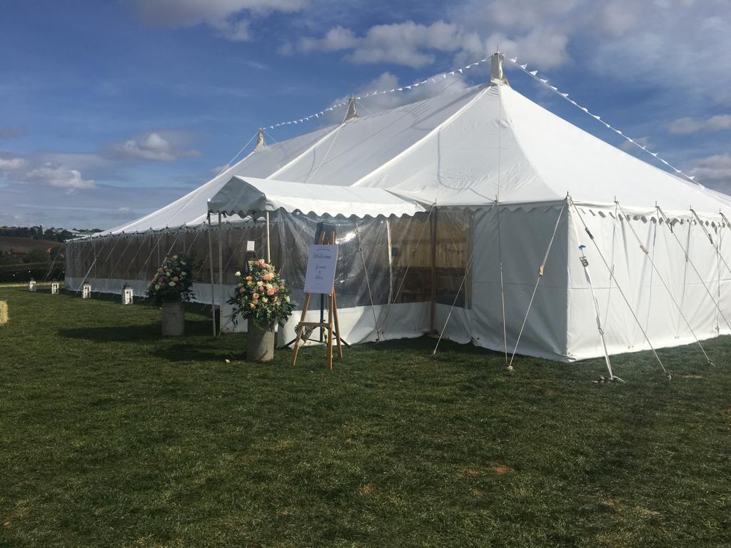 A large white tent is sitting in the middle of a grassy field.