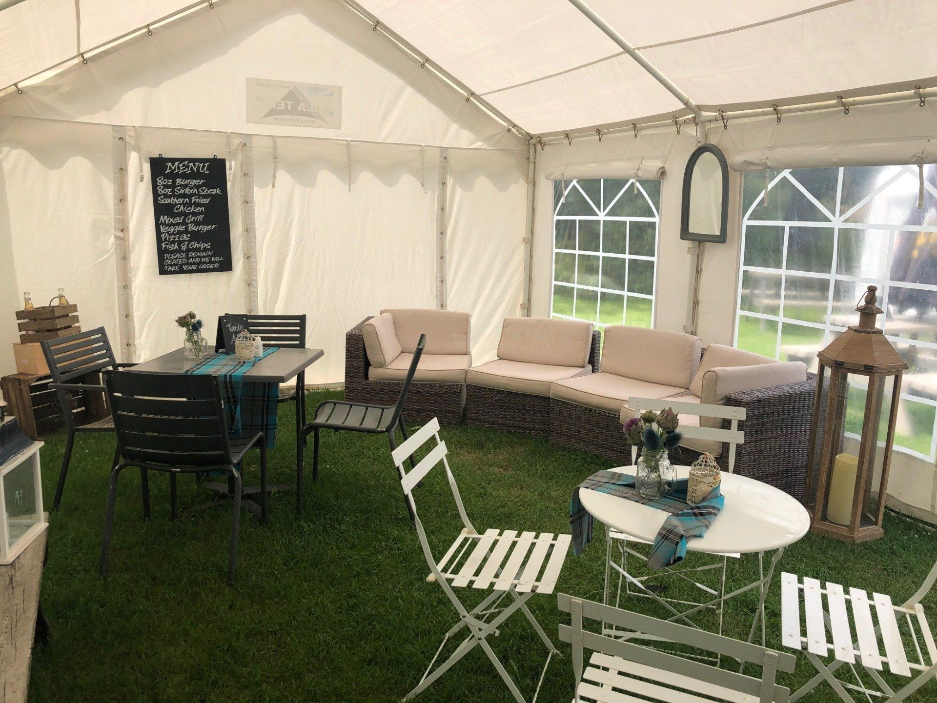 A tent with a couch , table and chairs inside of it.