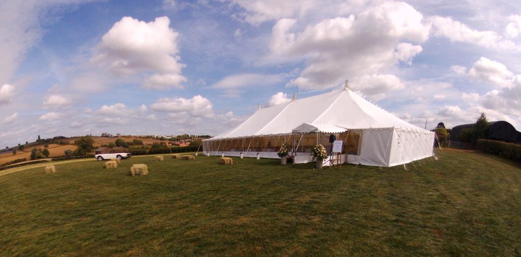 A large white tent is sitting in the middle of a grassy field.
