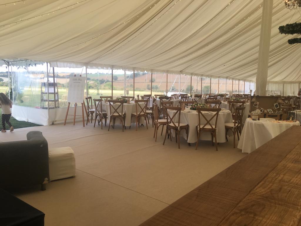 A large tent with tables and chairs set up for a wedding reception.