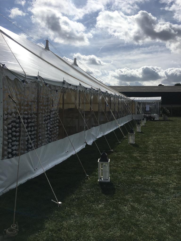 A long white tent is sitting in the middle of a grassy field.