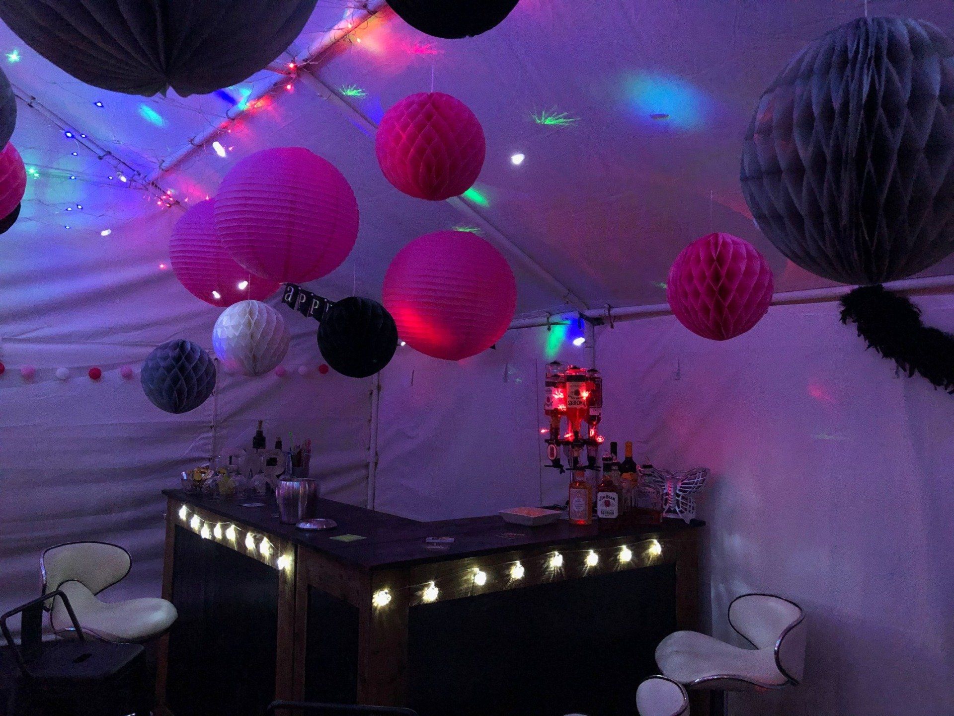 A party is being held in a tent with pink lanterns hanging from the ceiling.