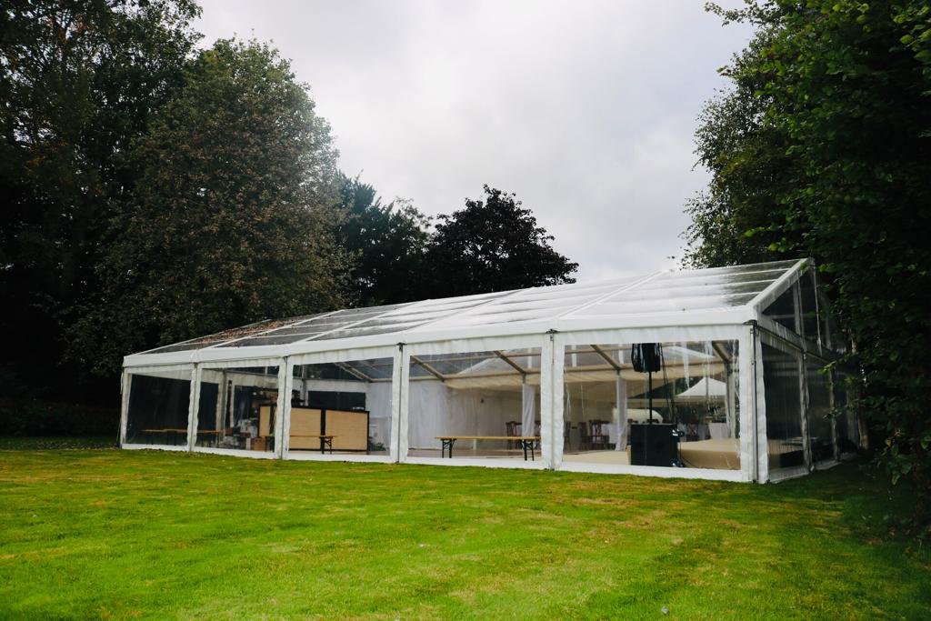 A large clear tent is sitting in the middle of a grassy field