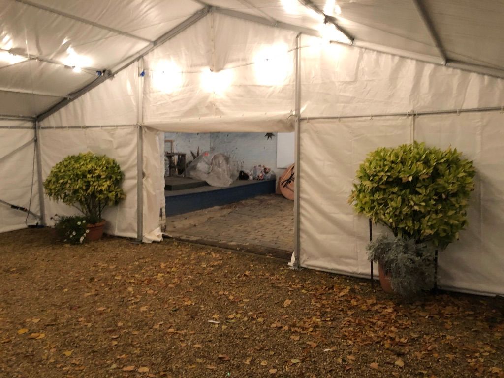 A white tent is sitting on top of a gravel driveway.