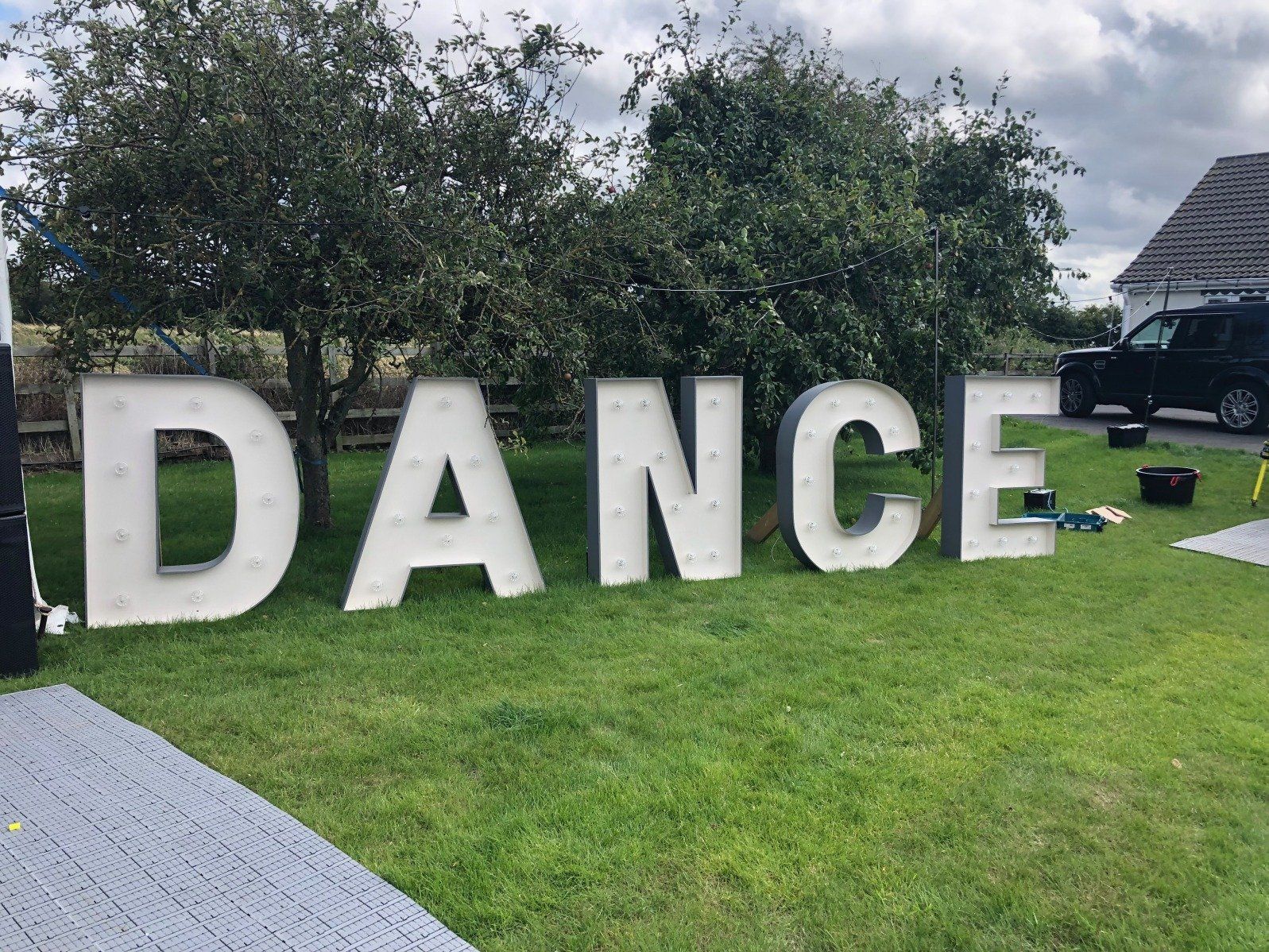 The word dance is written in large white letters on a lush green field.