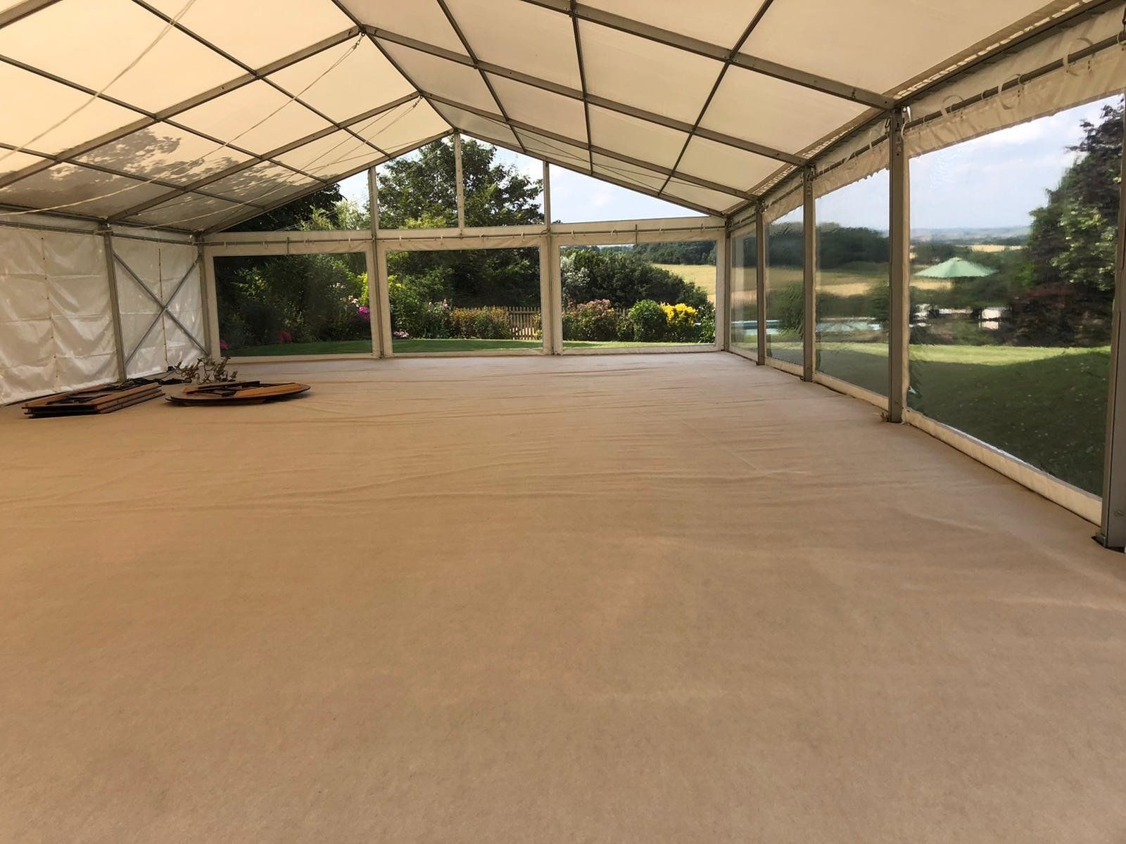 A large empty tent with a lot of windows and a carpeted floor.