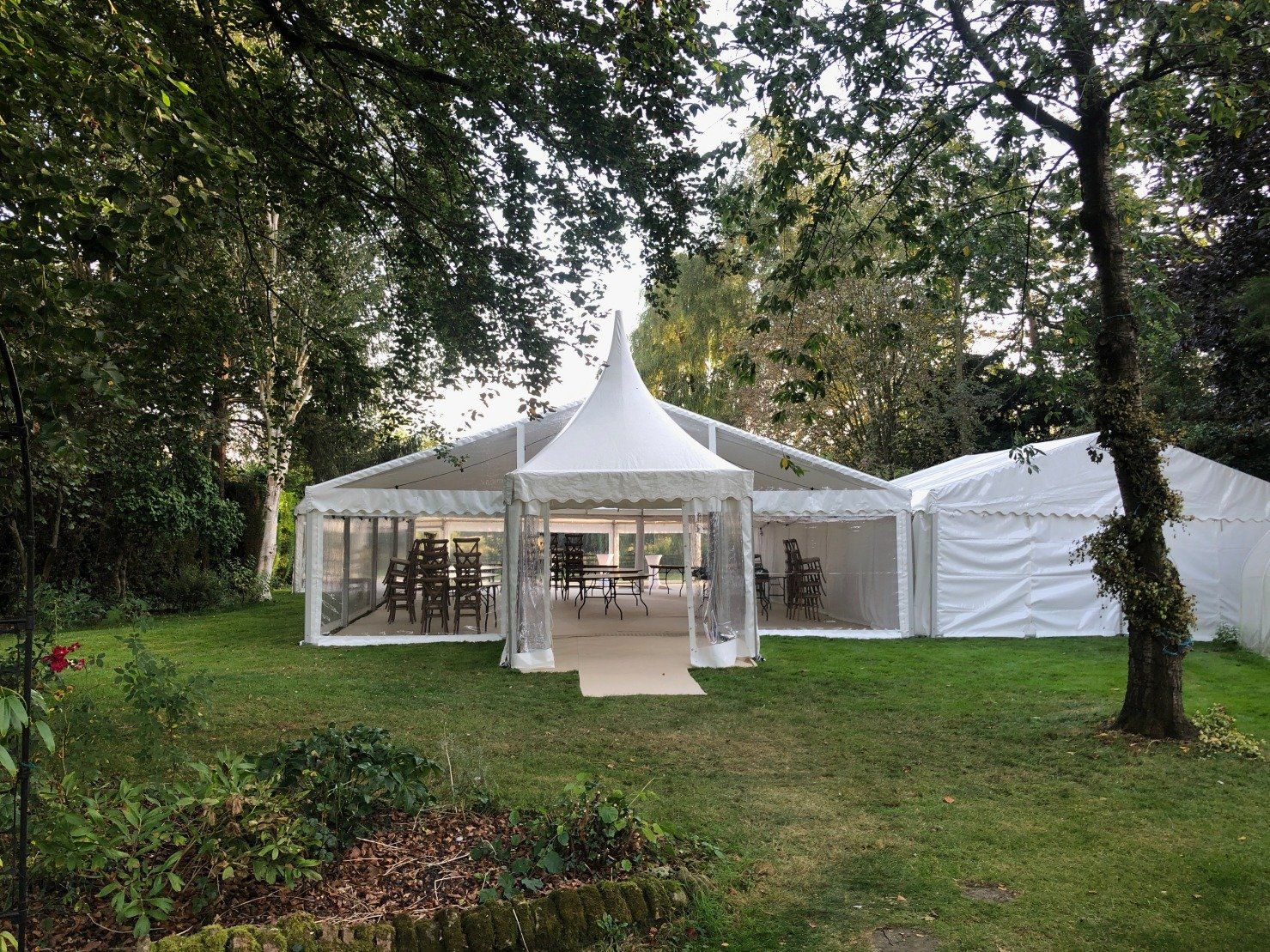 A large white tent is sitting in the middle of a lush green field.