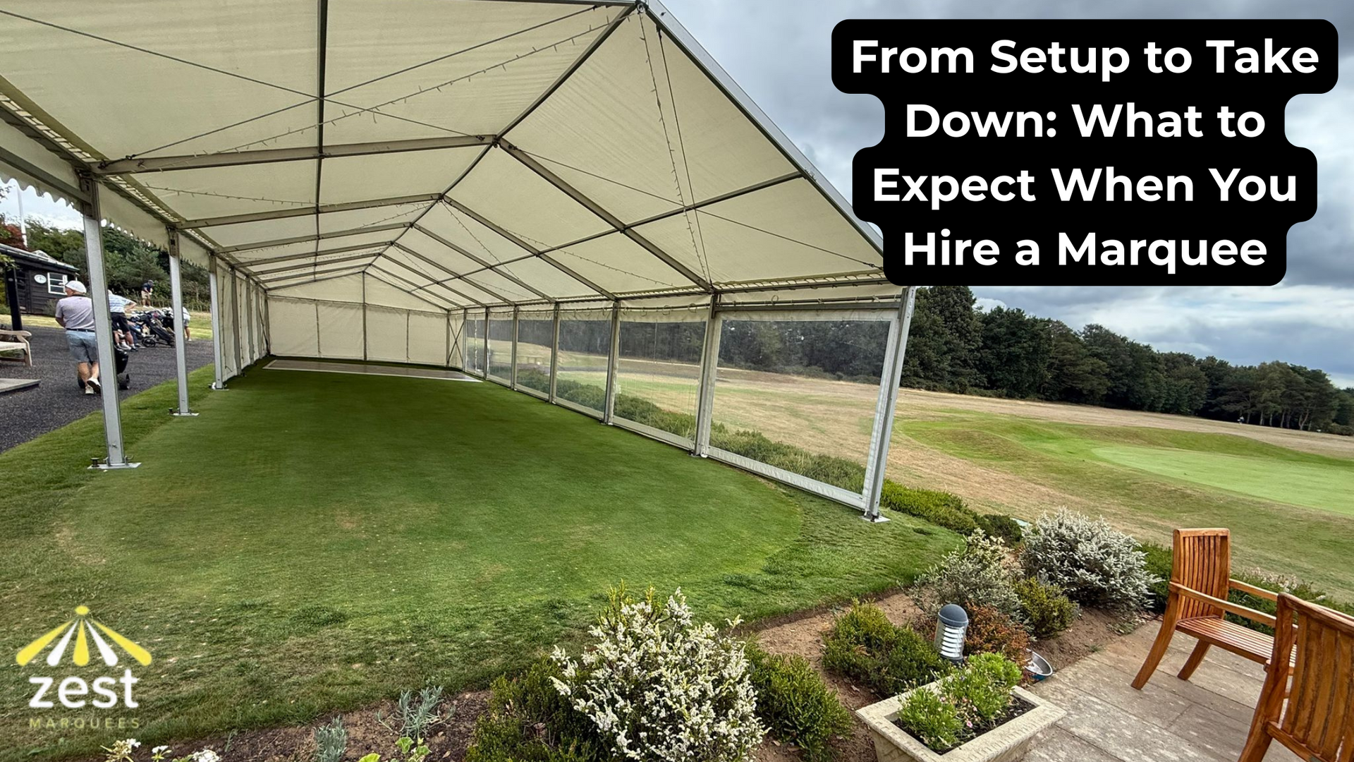 A long, white marquee tent set up on a grassy lawn with clear side panels, overlooking a field. Text reads 