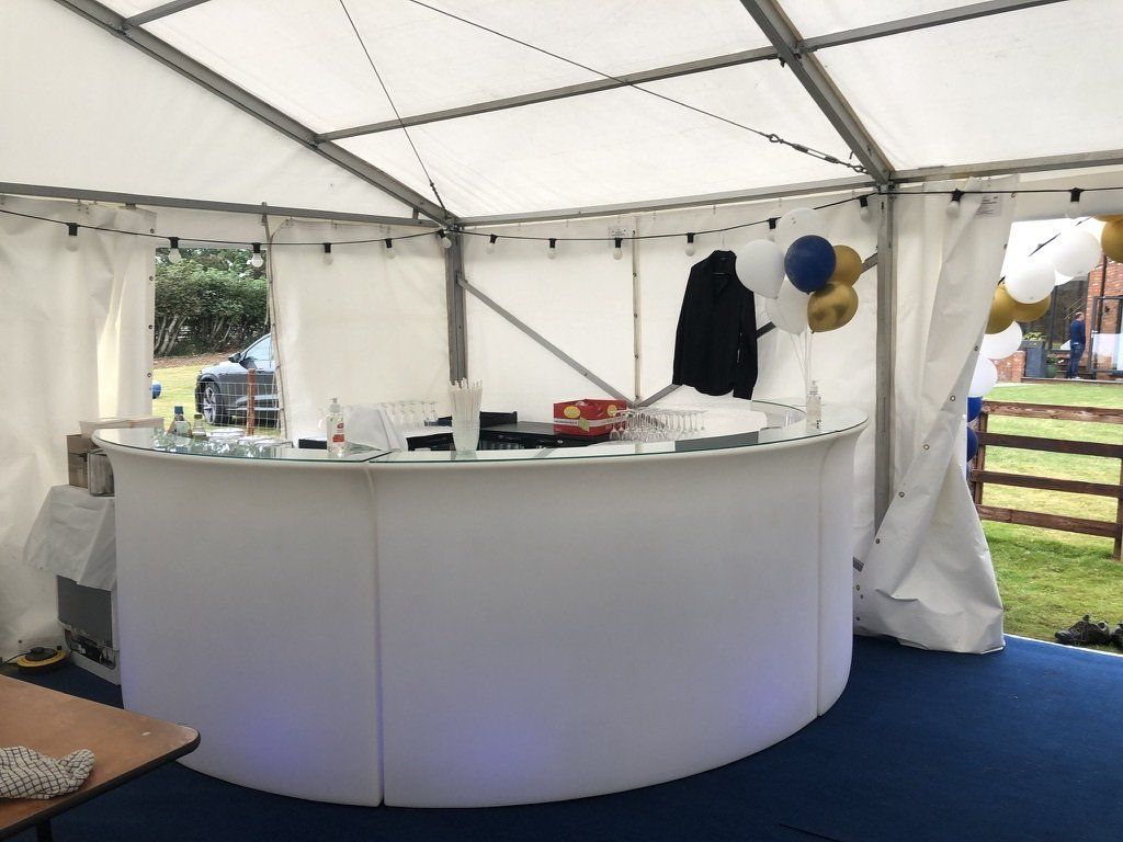 A white bar in a tent with balloons hanging from the ceiling.
