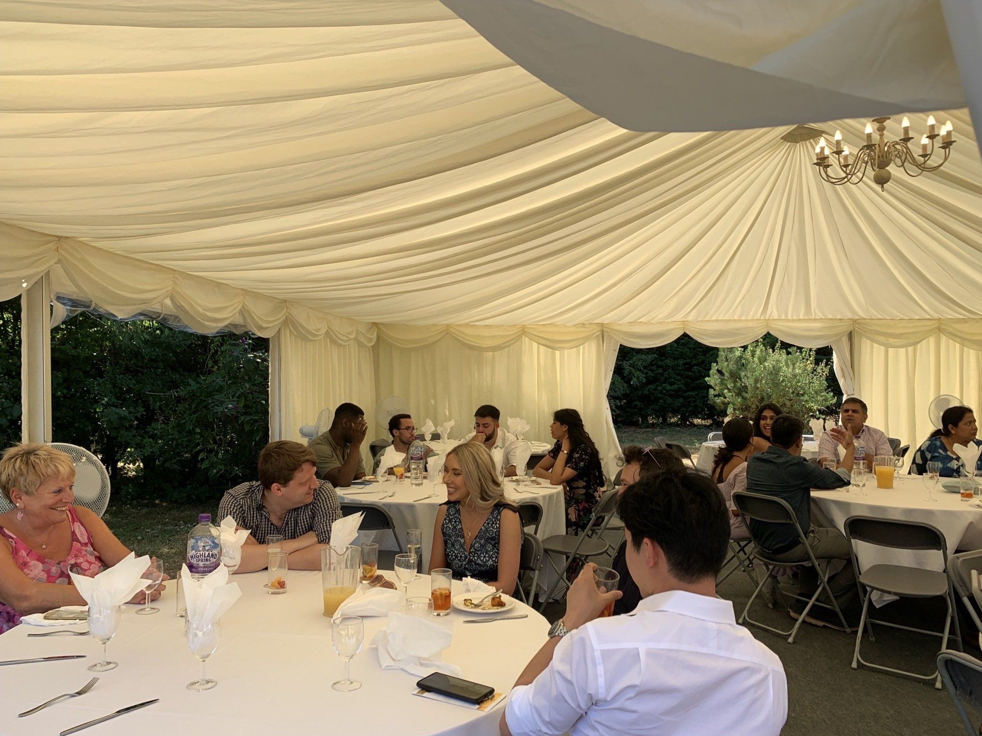 A group of people are sitting at tables under a tent.