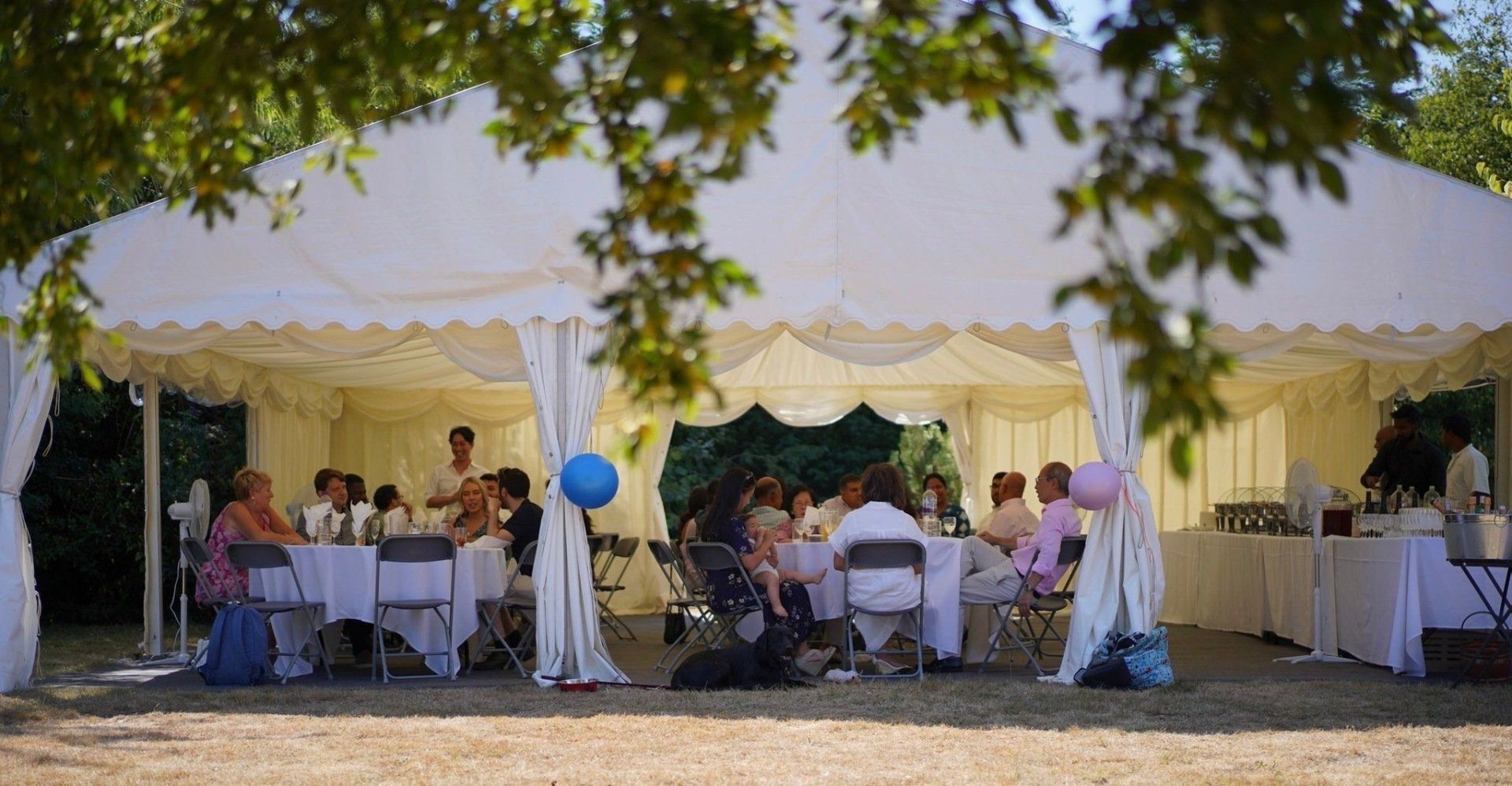 A group of people are sitting at tables under a tent.