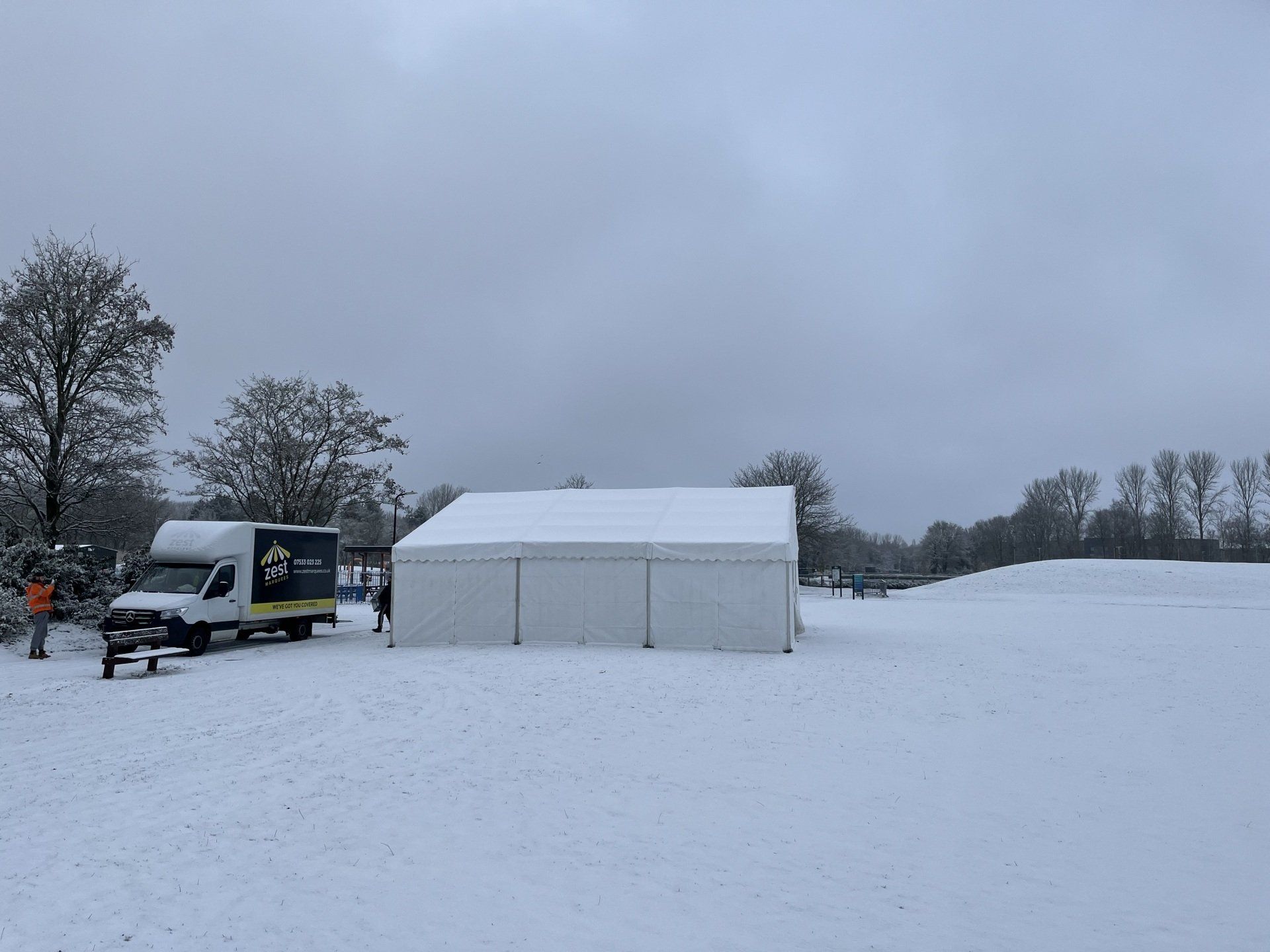 A white tent is sitting in the middle of a snow covered field.
