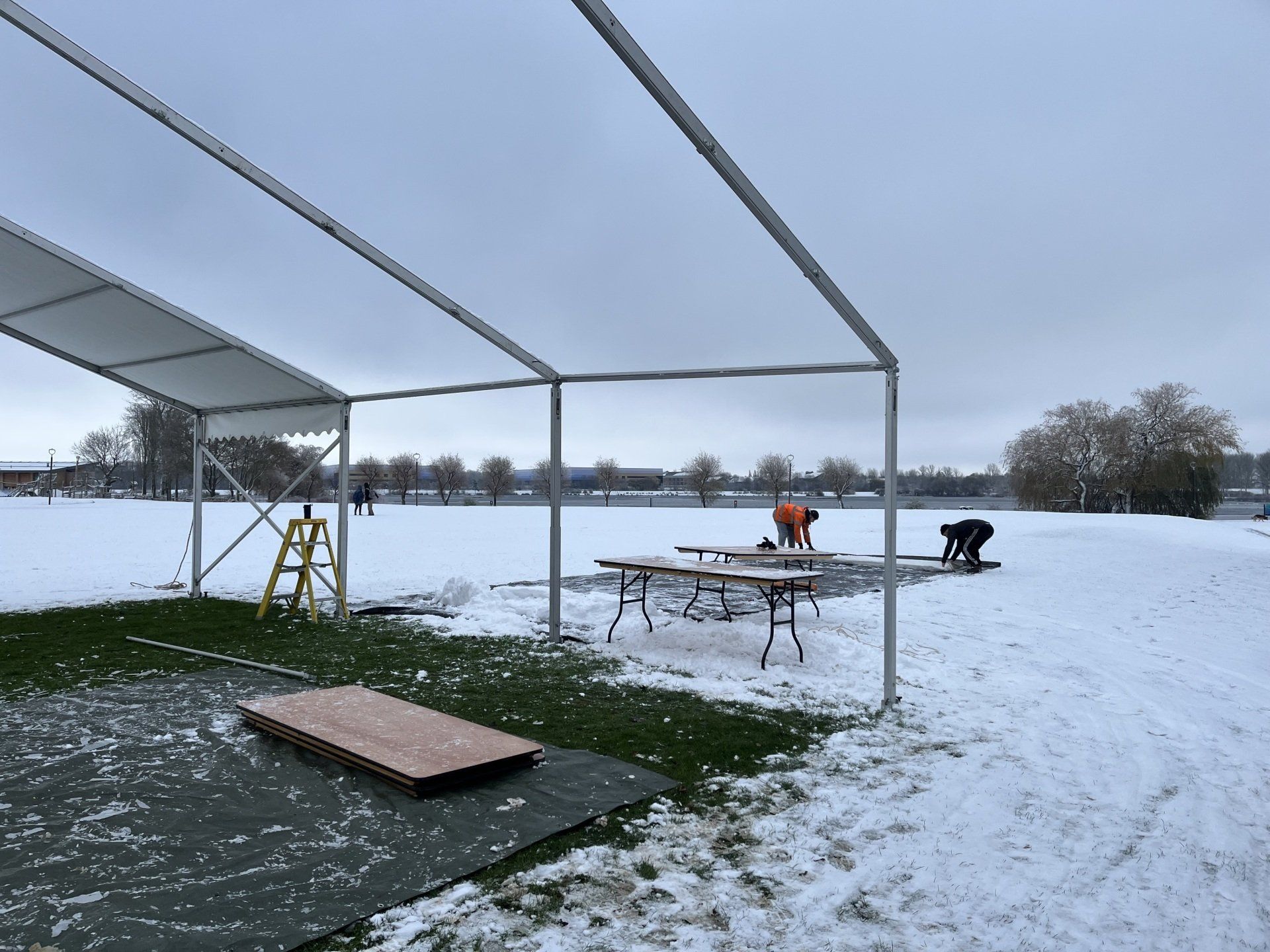 A group of people are working on a tent in the snow.