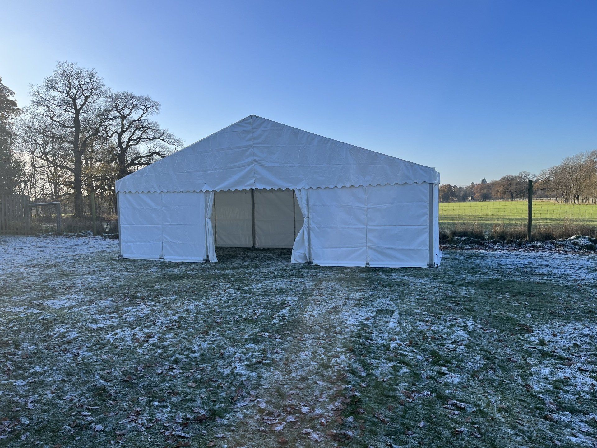 A large white tent is sitting in the middle of a snowy field.