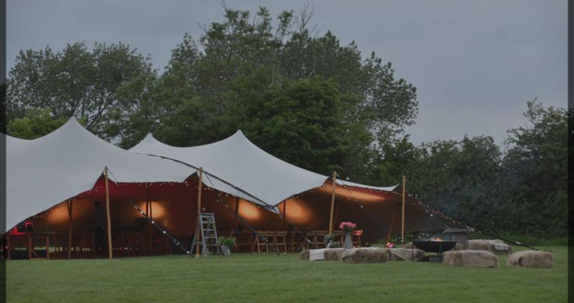 A large tent is sitting in the middle of a grassy field.