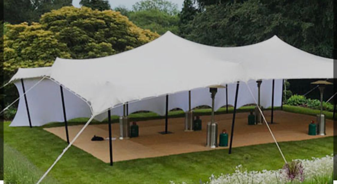 A large white tent is sitting on top of a lush green field.