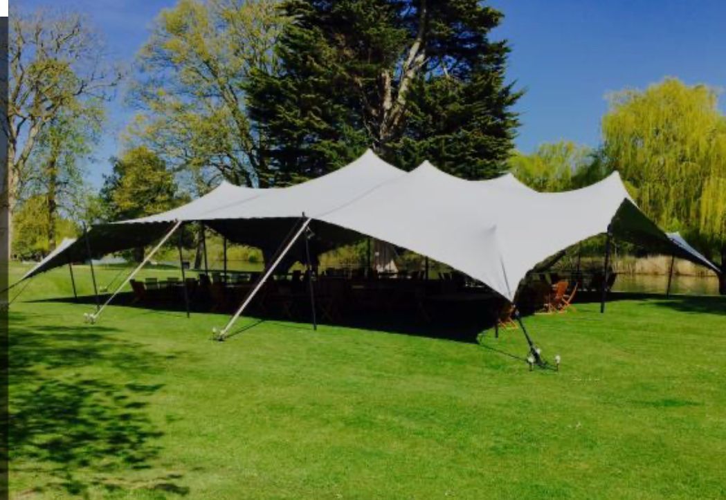 A large white tent is sitting on top of a lush green field.