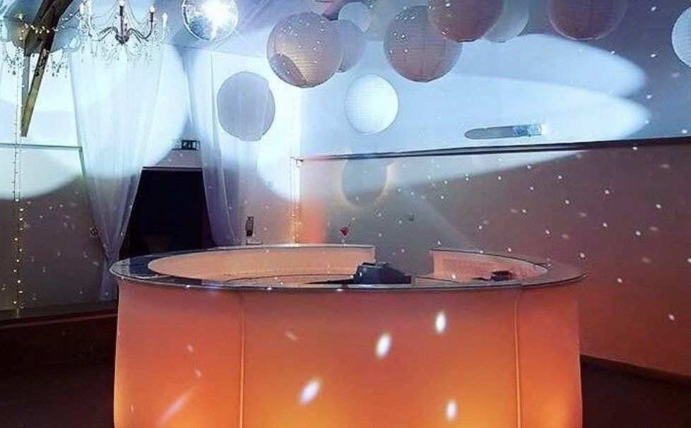 A round table is lit up in a room with balloons hanging from the ceiling.