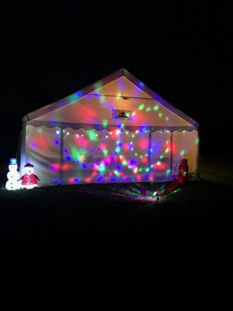 A tent is lit up at night with christmas lights and snowmen.
