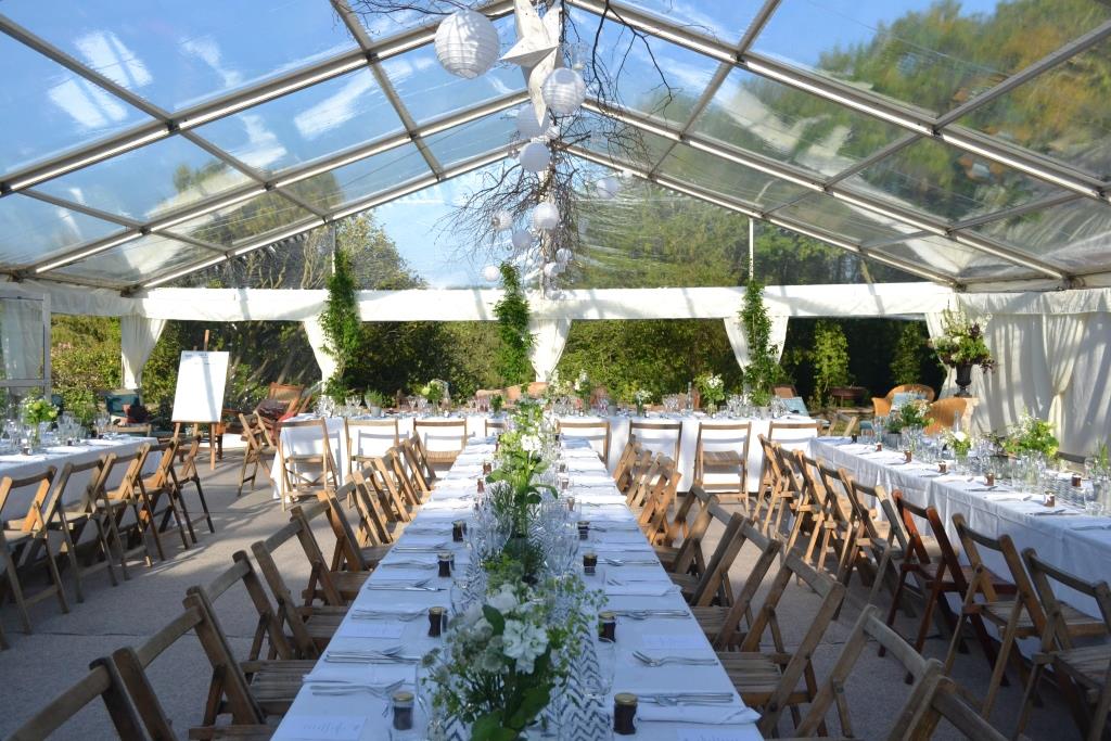 A long table and chairs under a clear tent.