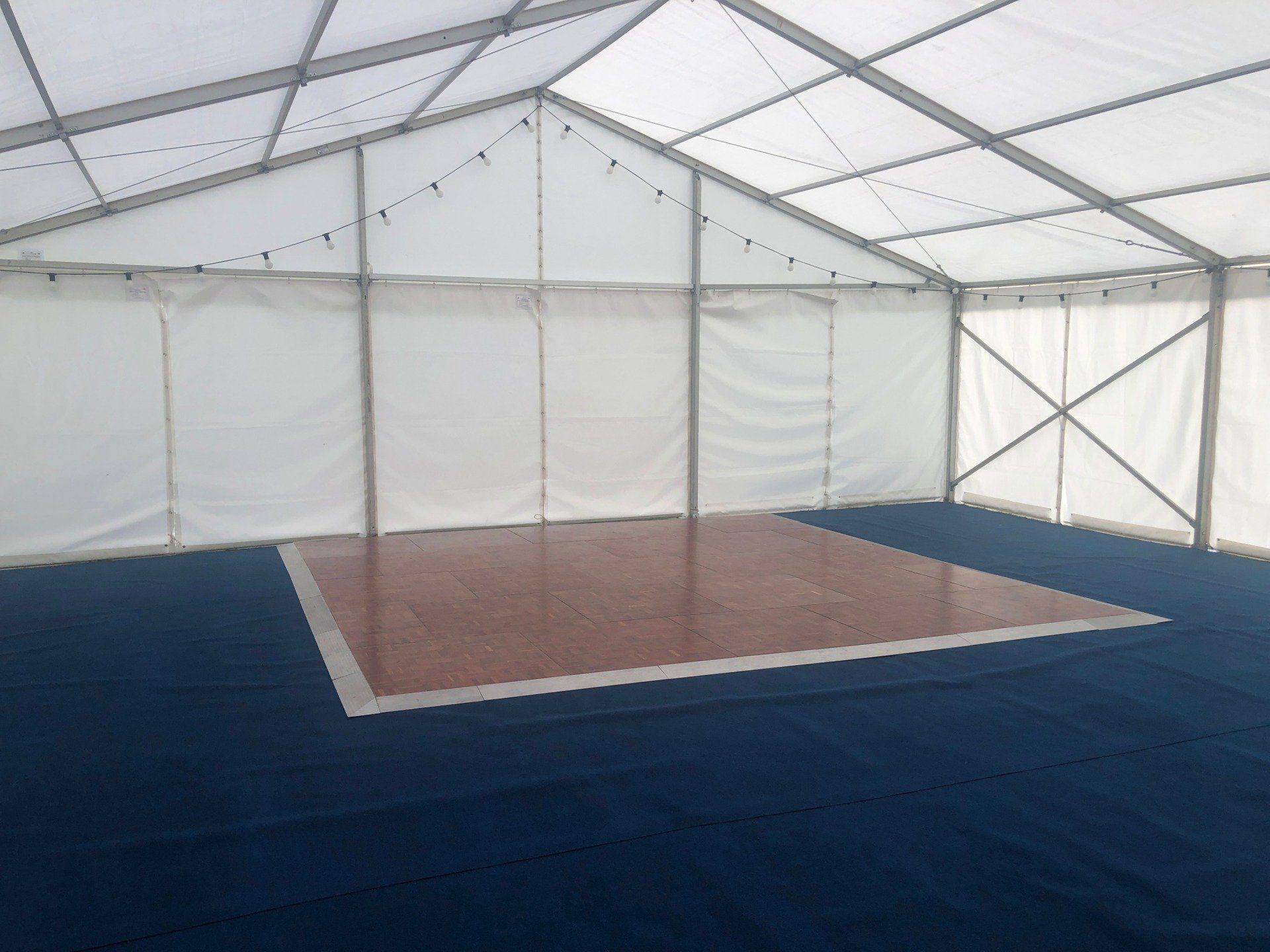 An empty tent with a dance floor in the middle