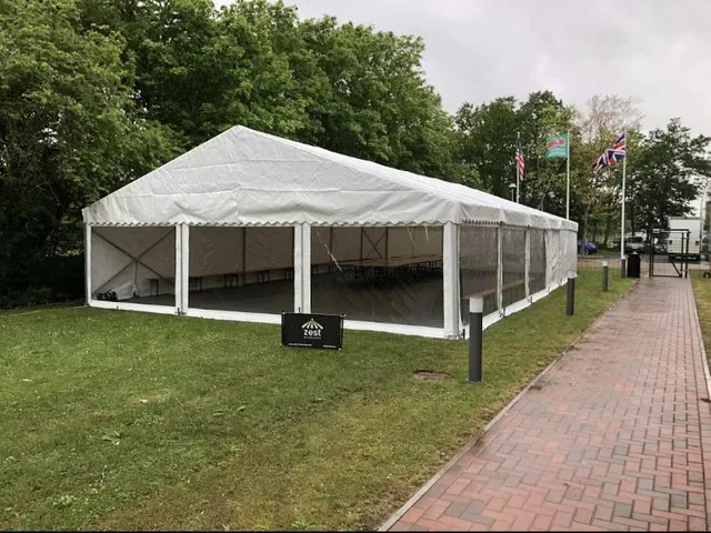 A large white tent is sitting on top of a lush green field.