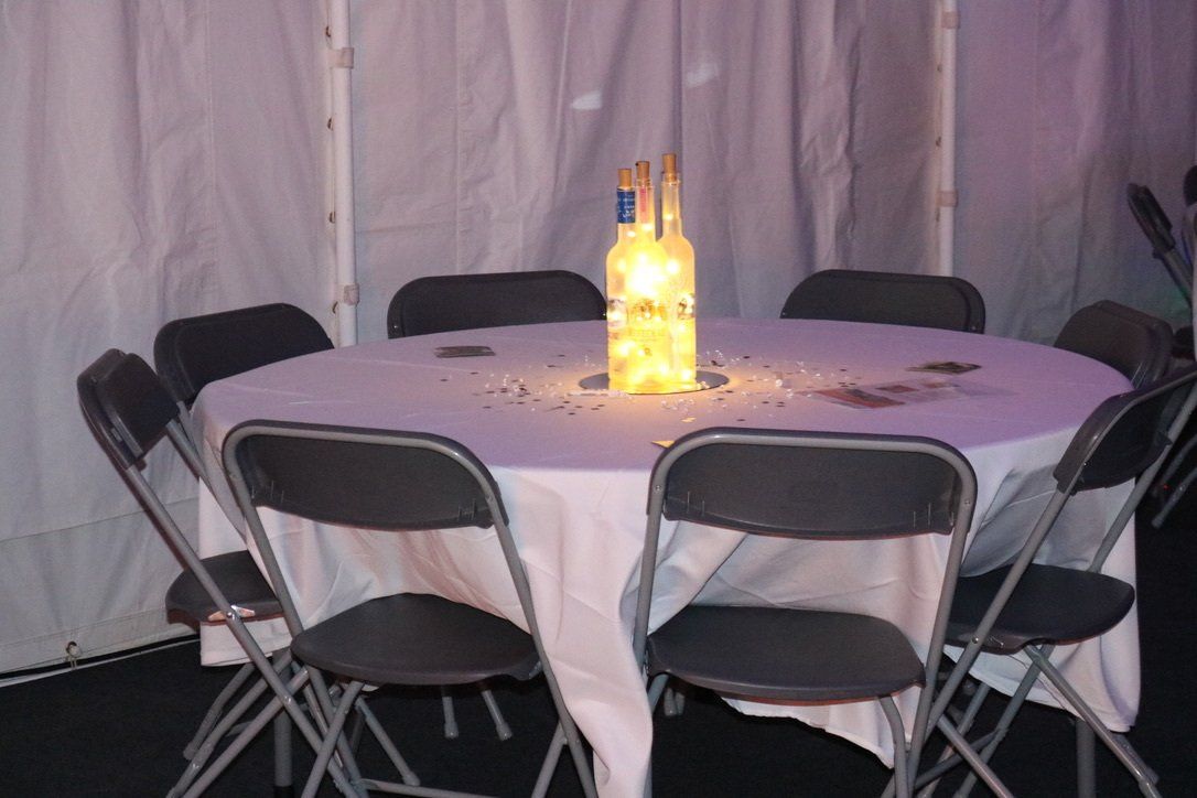 A round table with a white table cloth and black folding chairs