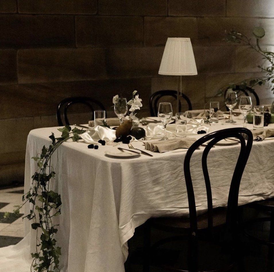 A table with a white table cloth and a lamp on it