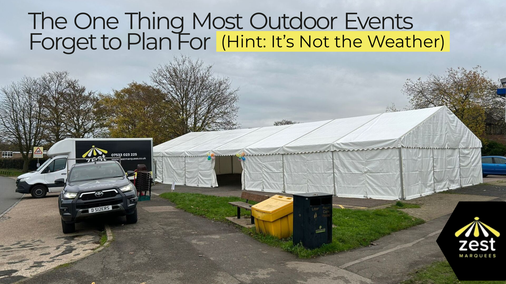 A large white tent with vehicles parked outside. Text reads