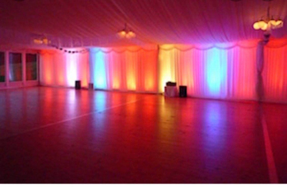 An empty dance floor with colorful lights on the walls and ceiling.